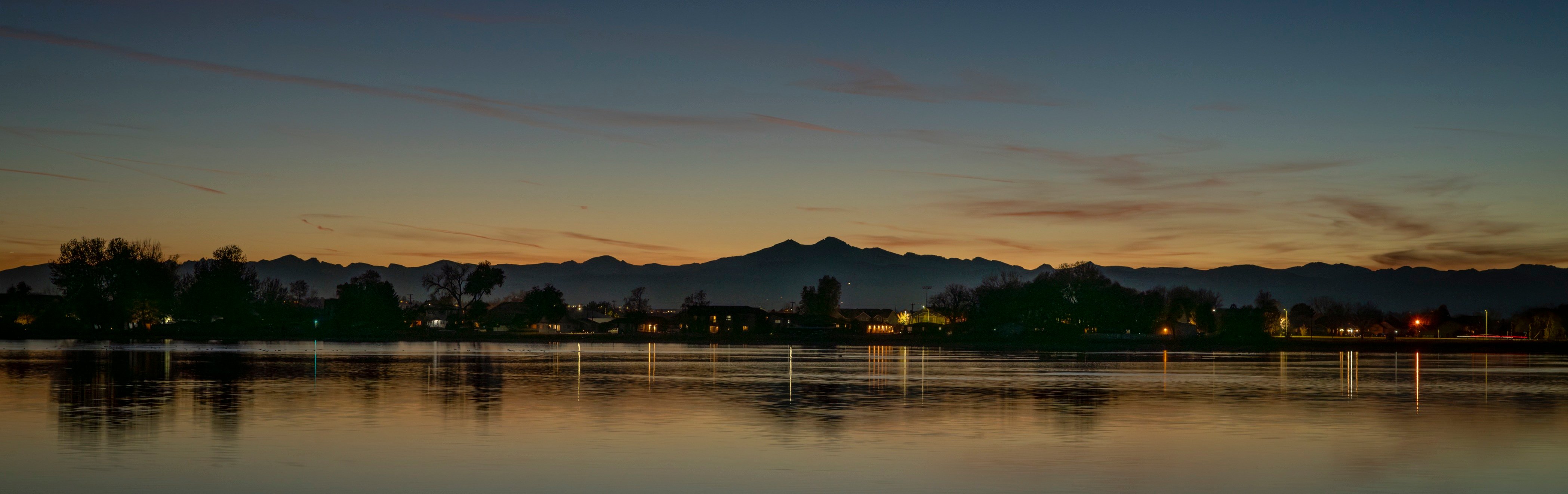 A body of water with trees and mountains in the background.