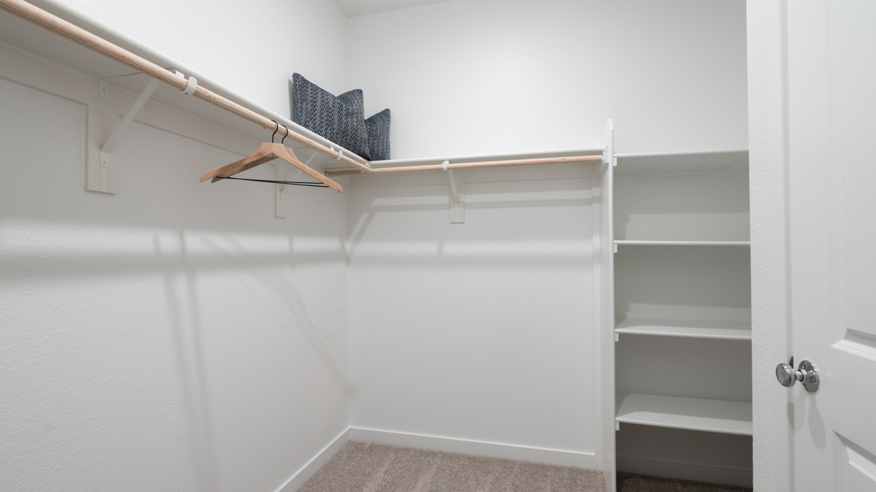 A white wall with a shelf and a chair.