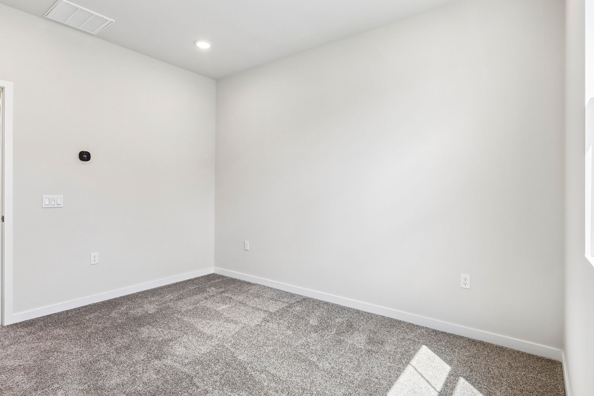 A room with a carpet and a white wall.