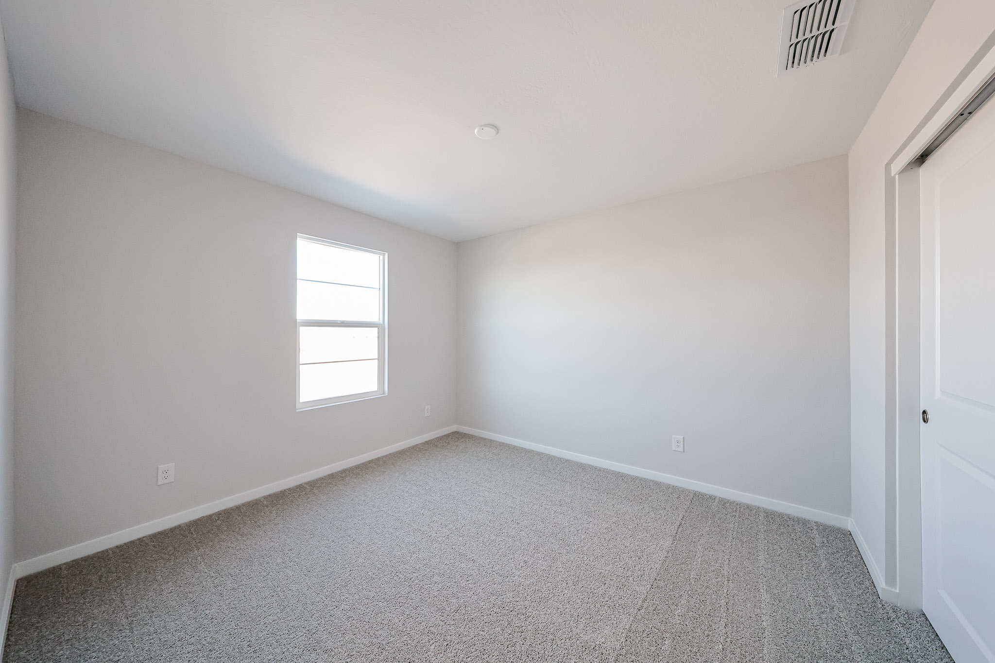 A room with a carpet and a window.