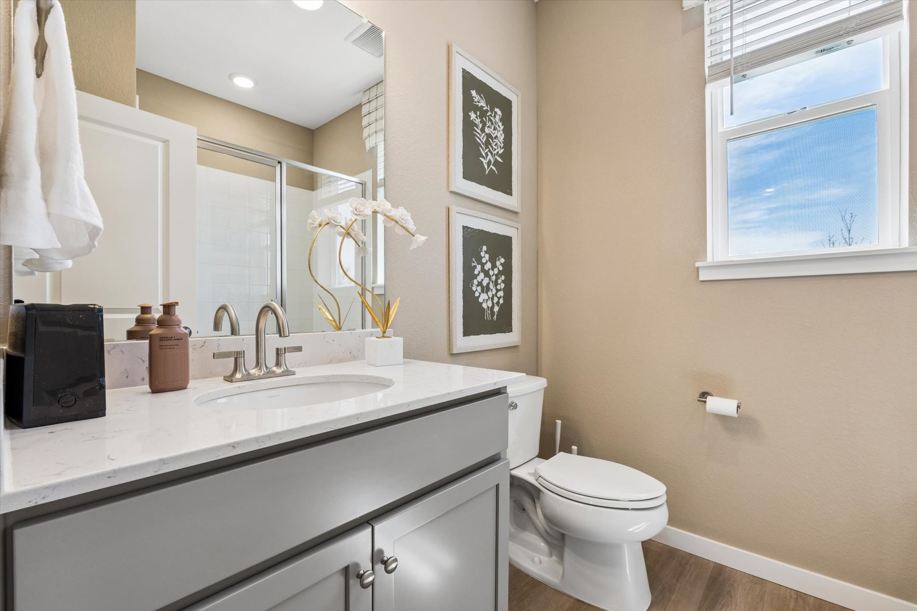 A bathroom with a sink toilet and mirror.