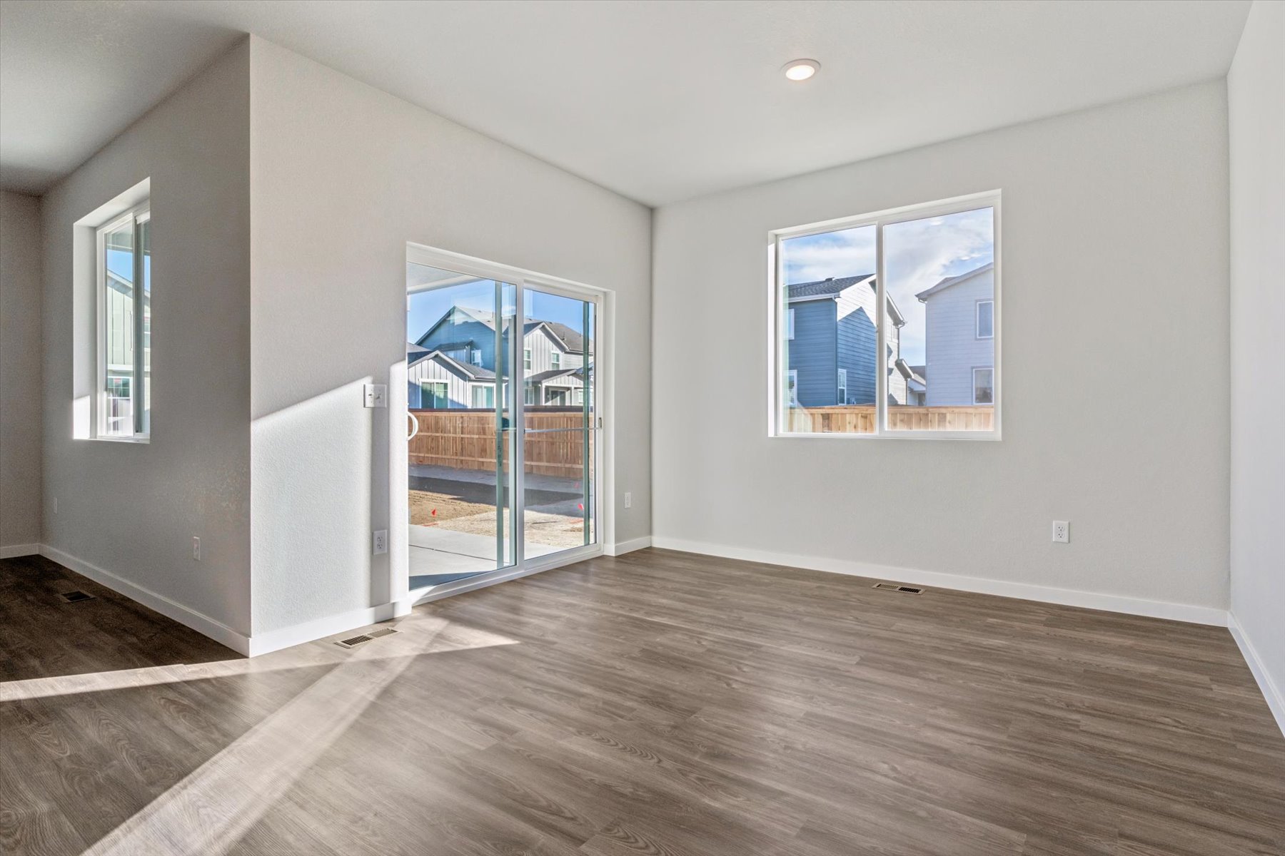 A room with a wood floor and a glass door with a view of the ocean.