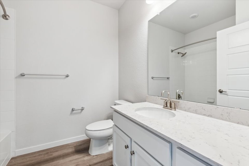 A bathroom with a sink toilet and mirror.