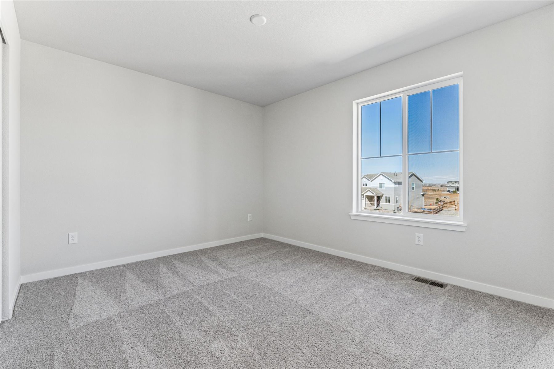 A room with a window and a white wall.