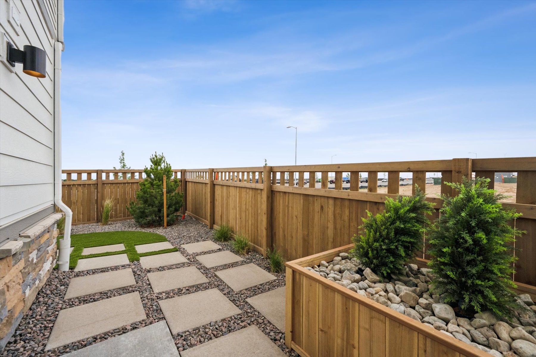 A fenced in yard with a stone walkway and a building.