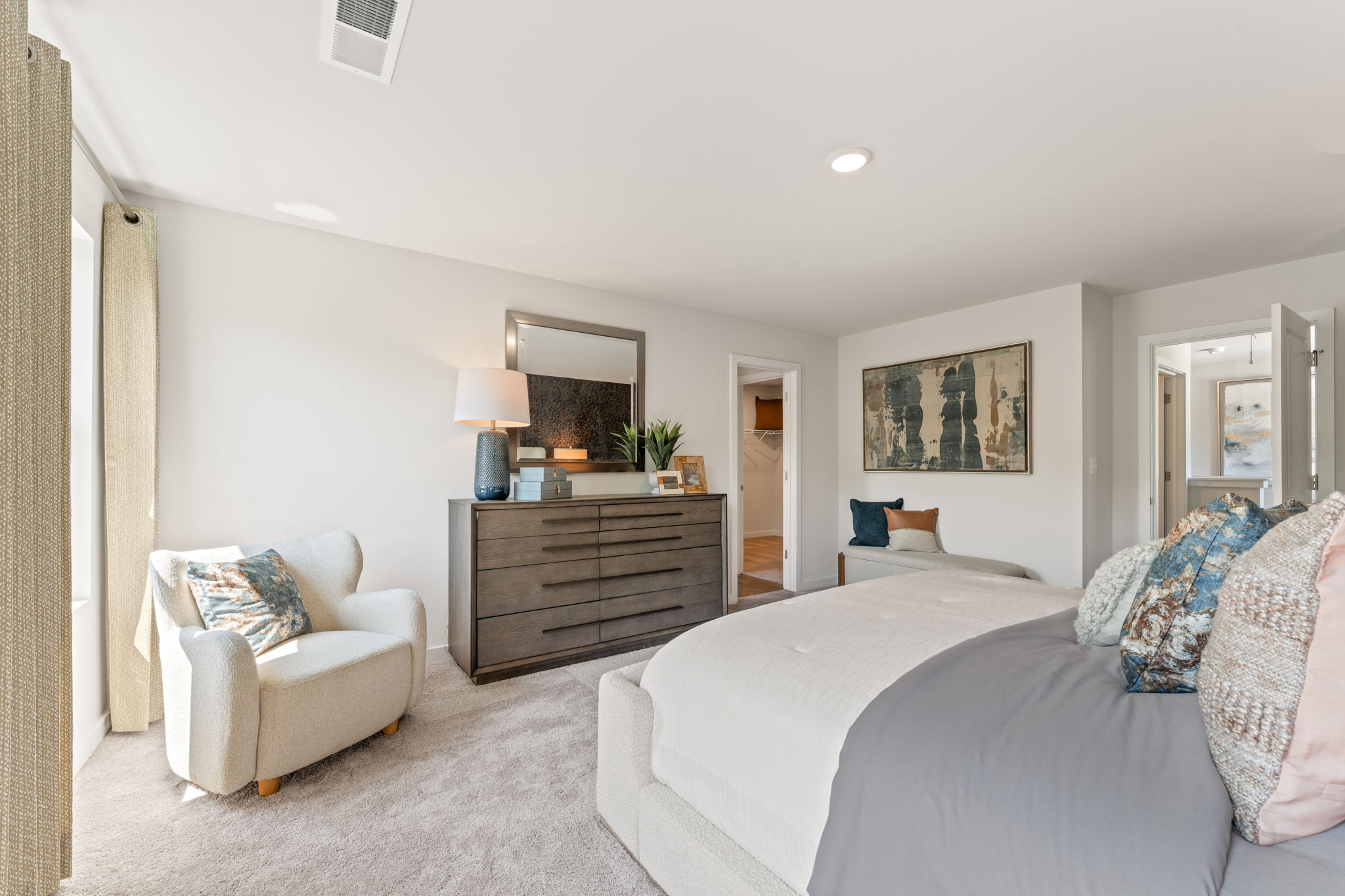 A bedroom with a bed and a chair.