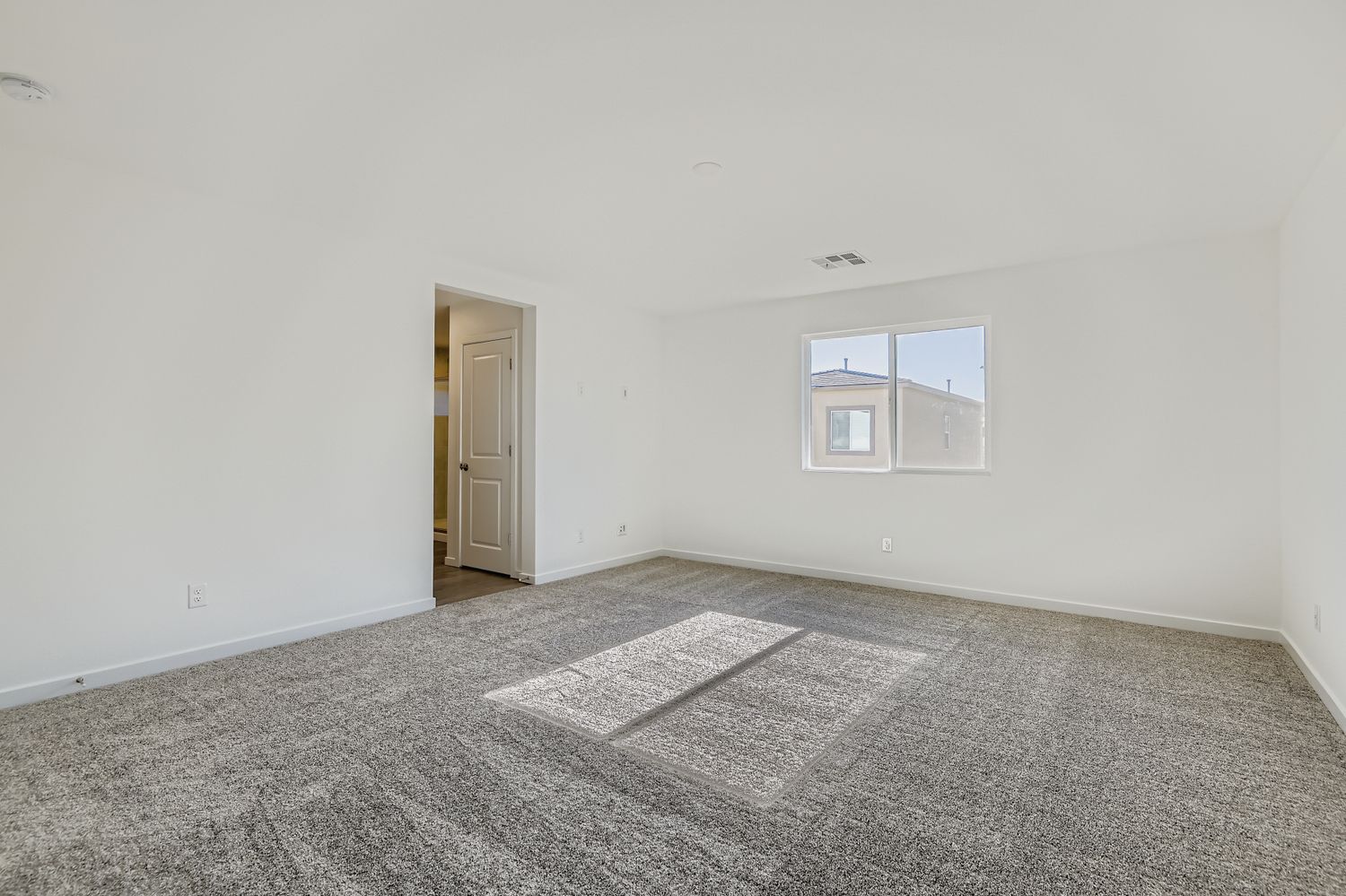 A room with a carpet and a door.