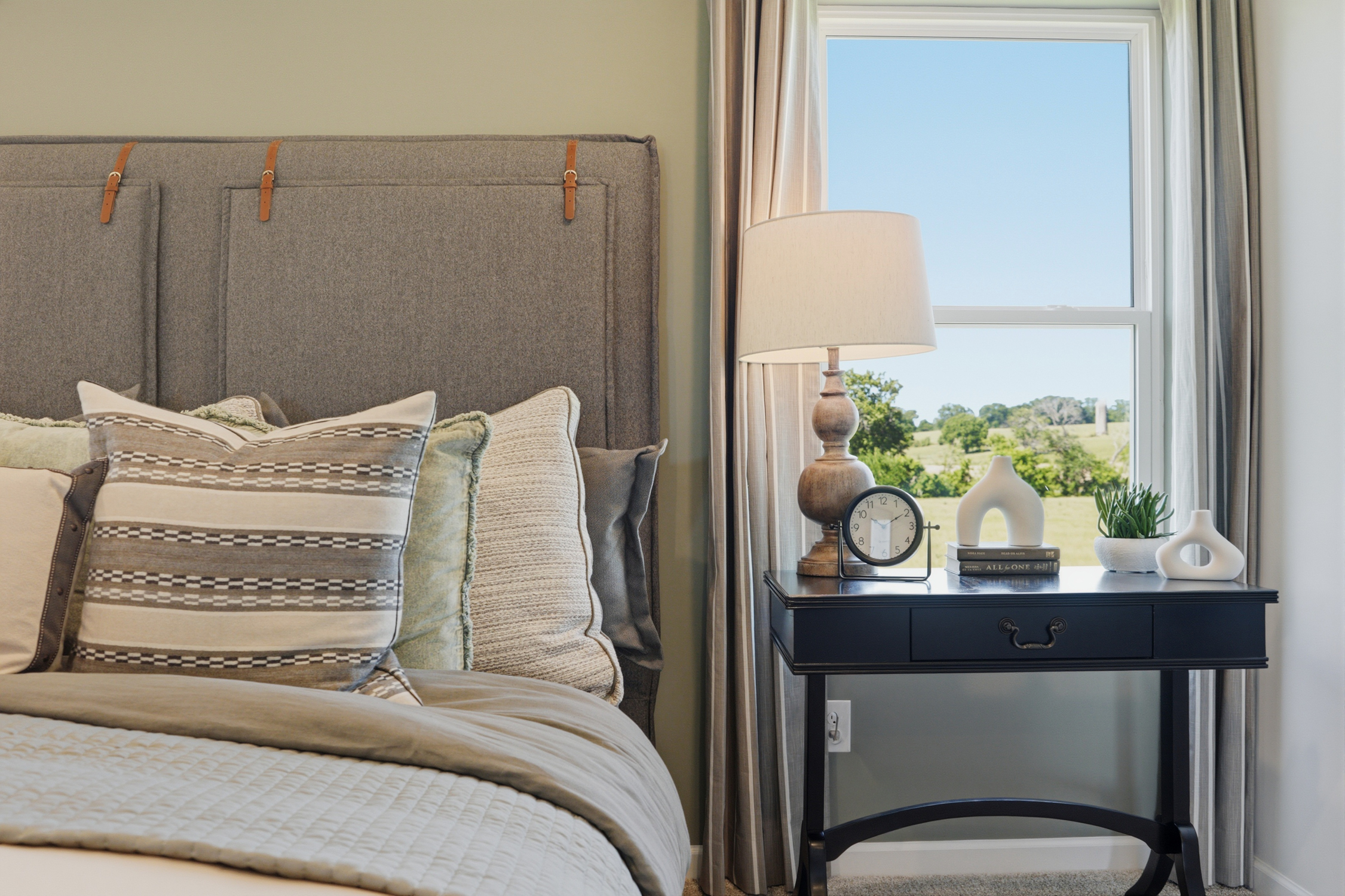 A bed with a lamp and a table with a clock on it.