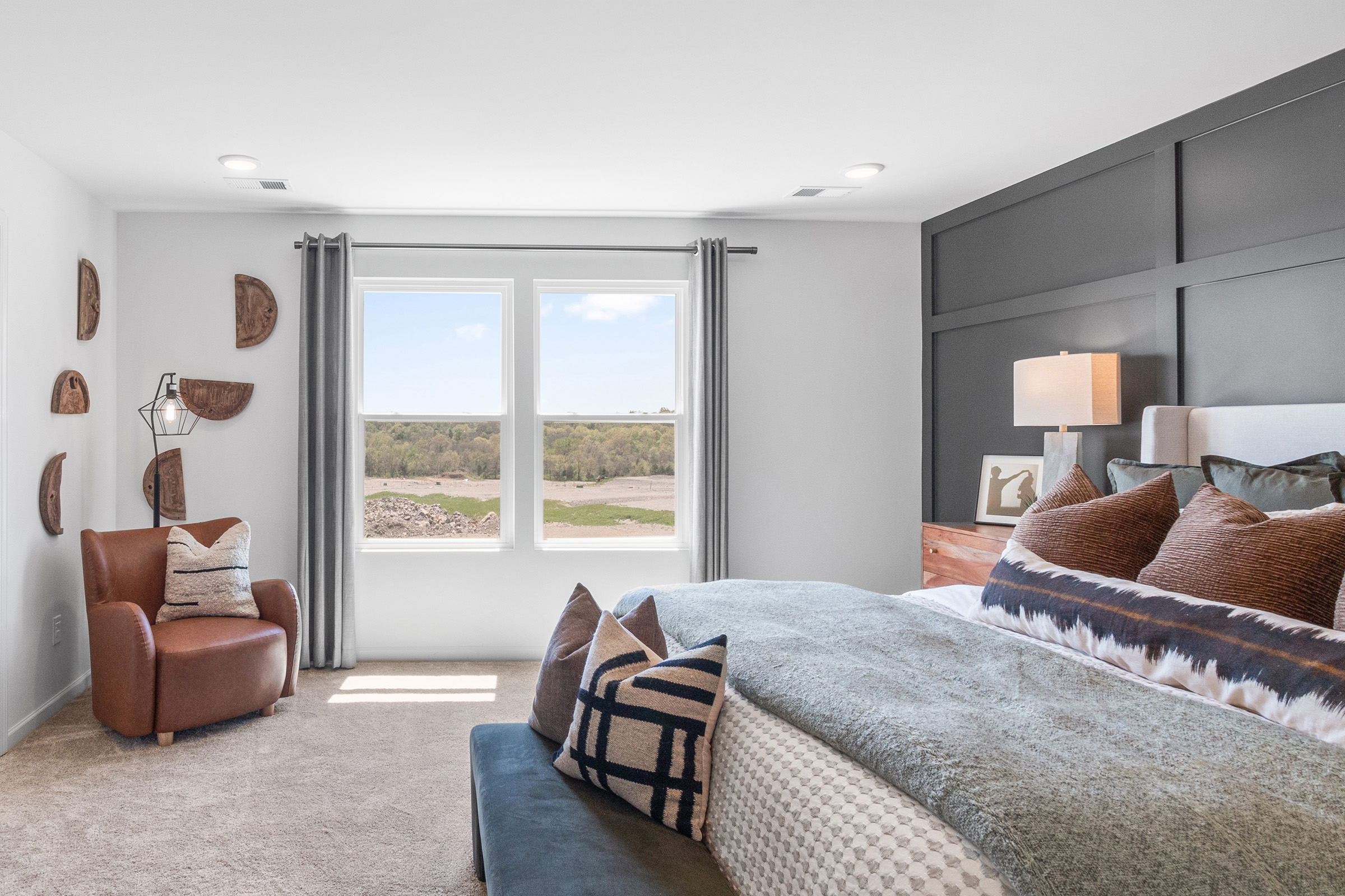 A bedroom with a bed and a chair.