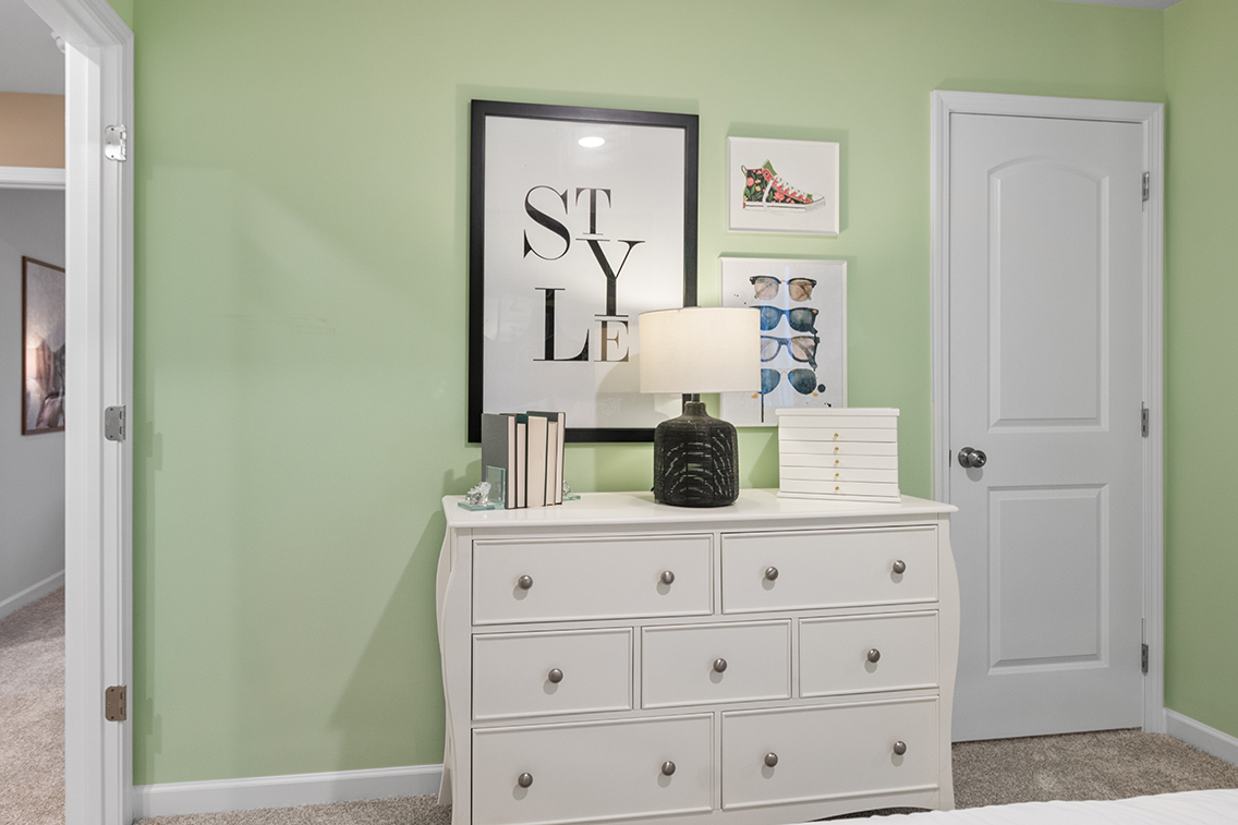 A white dresser with a lamp on top of it.
