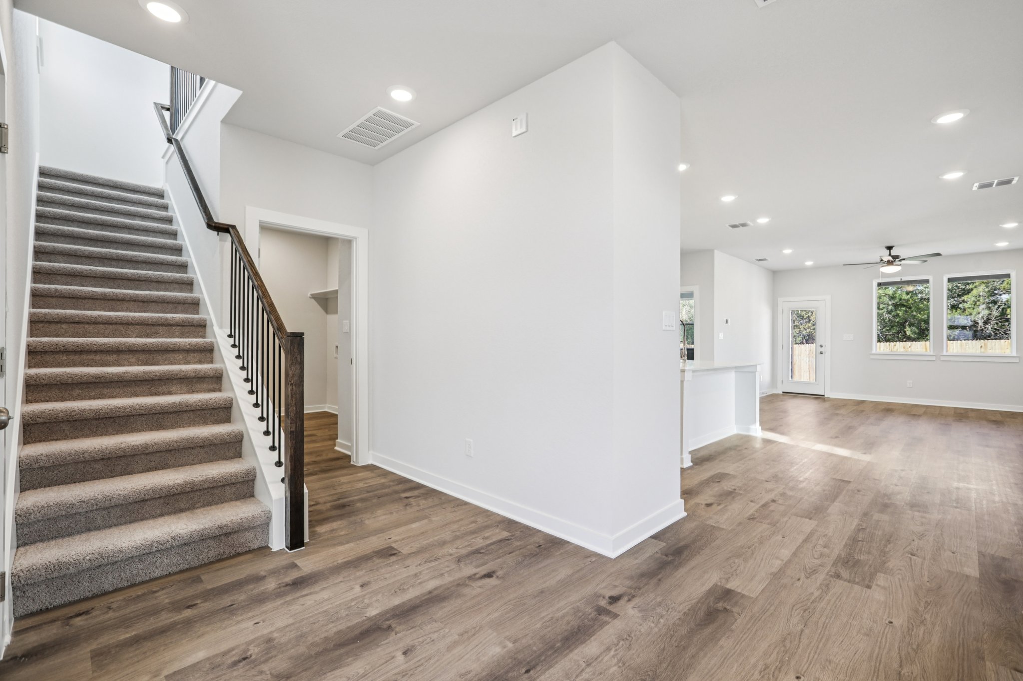 A large white room with a wood floor and a wood staircase.