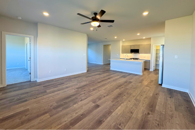 A large empty room with a wood floor and a ceiling fan.