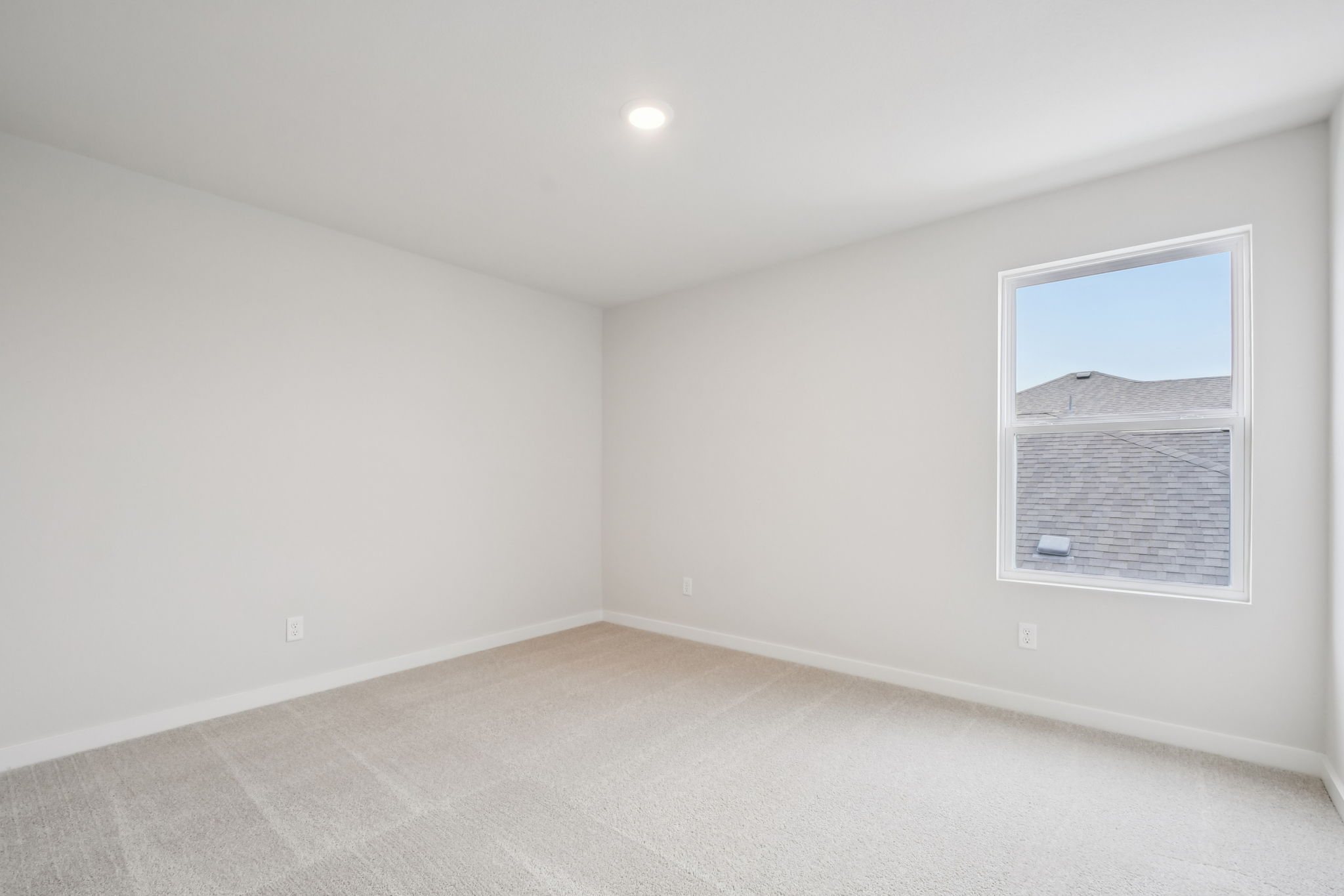 A room with a window and a white wall.