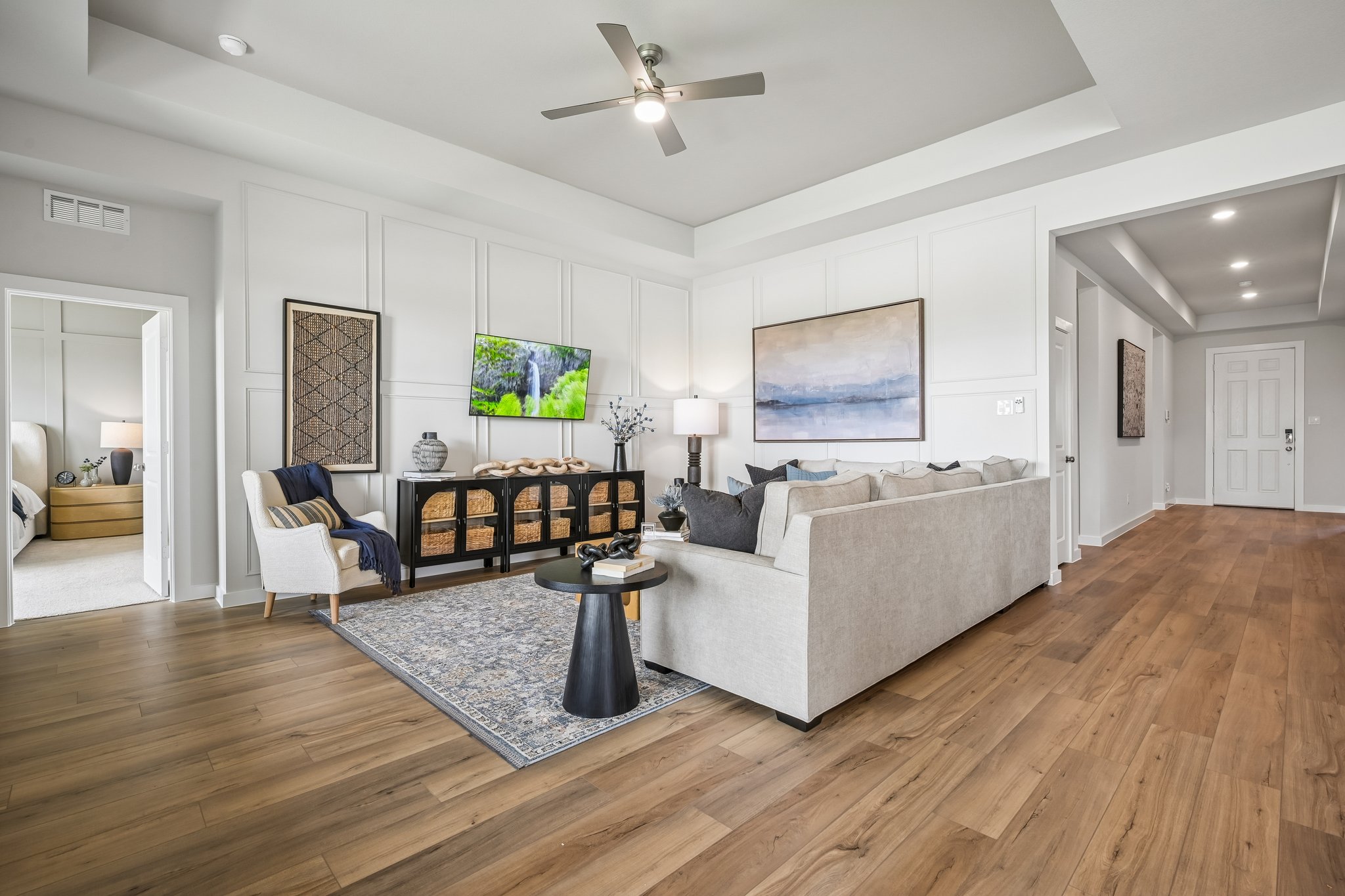 A living room with a large white couch and a wood floor.