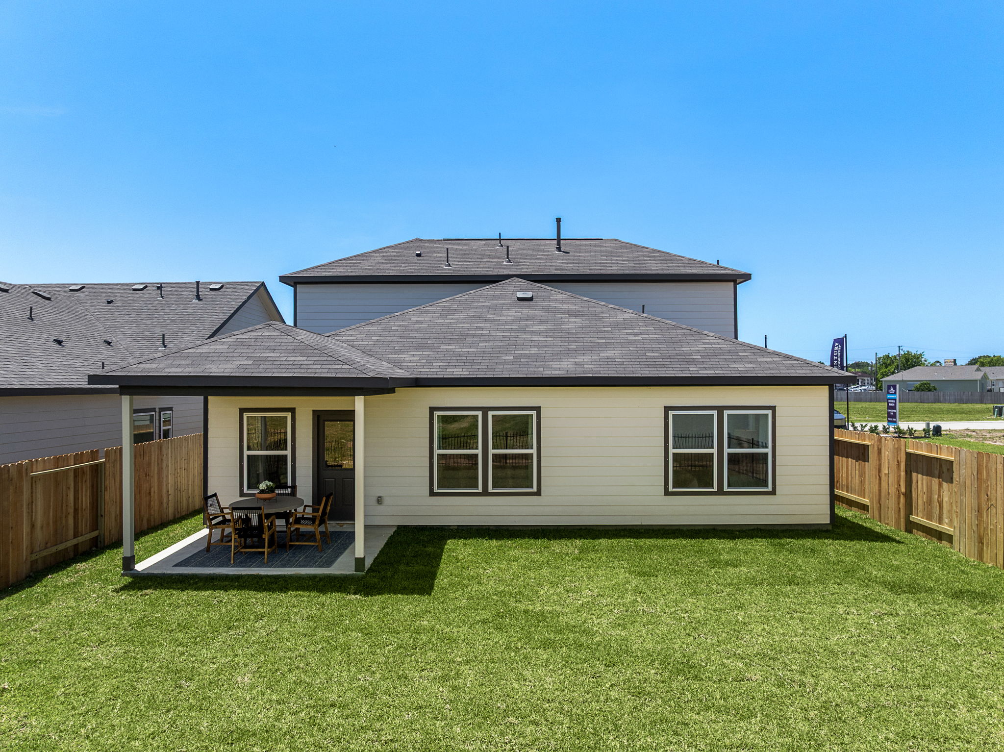 A house with a fence and a lawn in front of it.
