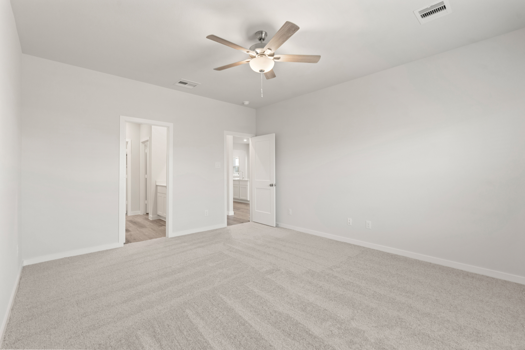 A room with a ceiling fan and a carpet.