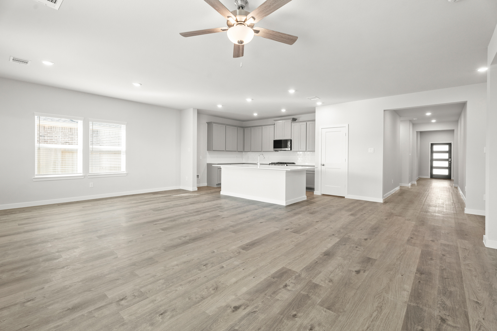 A large empty room with a wood floor and a ceiling fan.