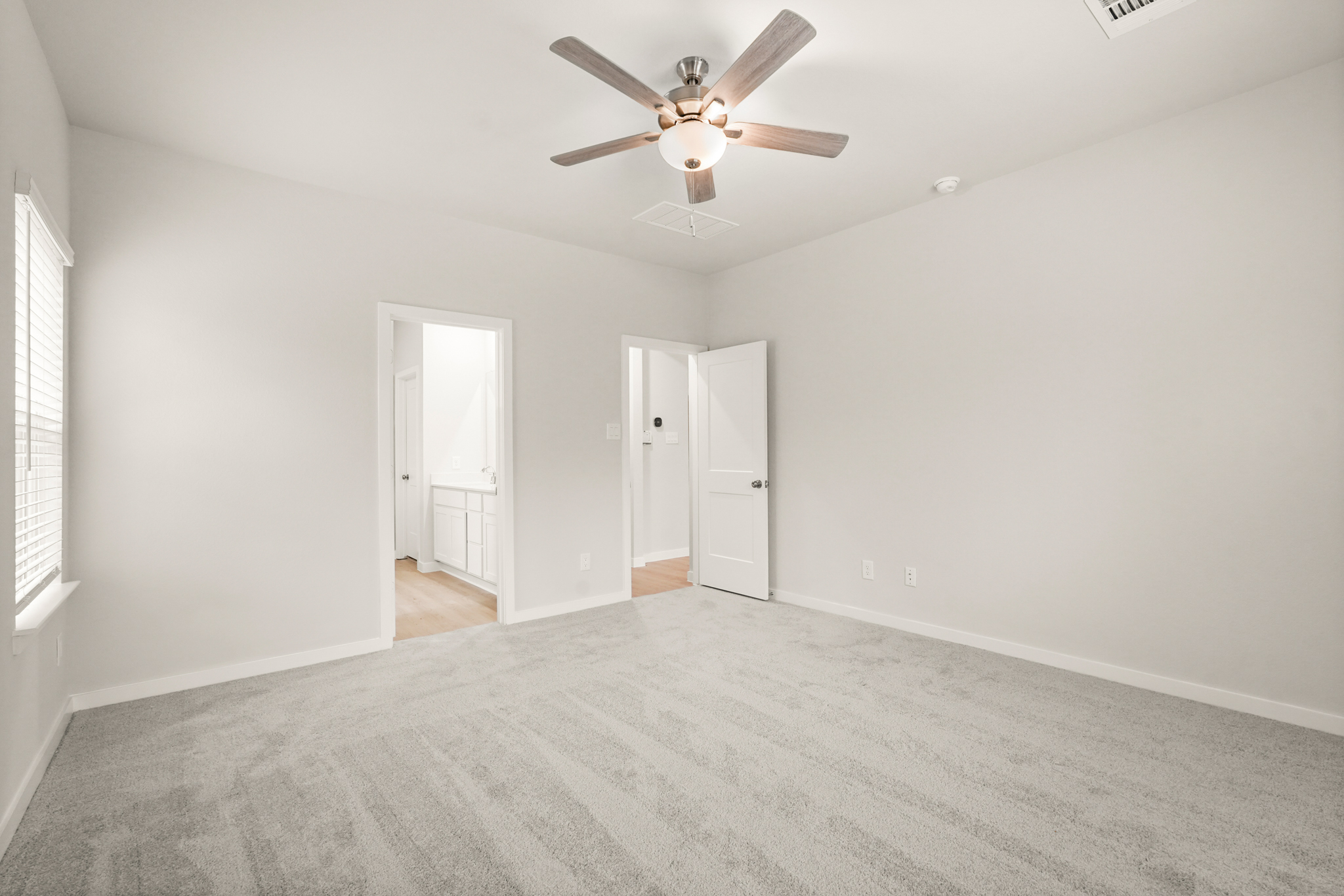 A room with a ceiling fan and a carpet.