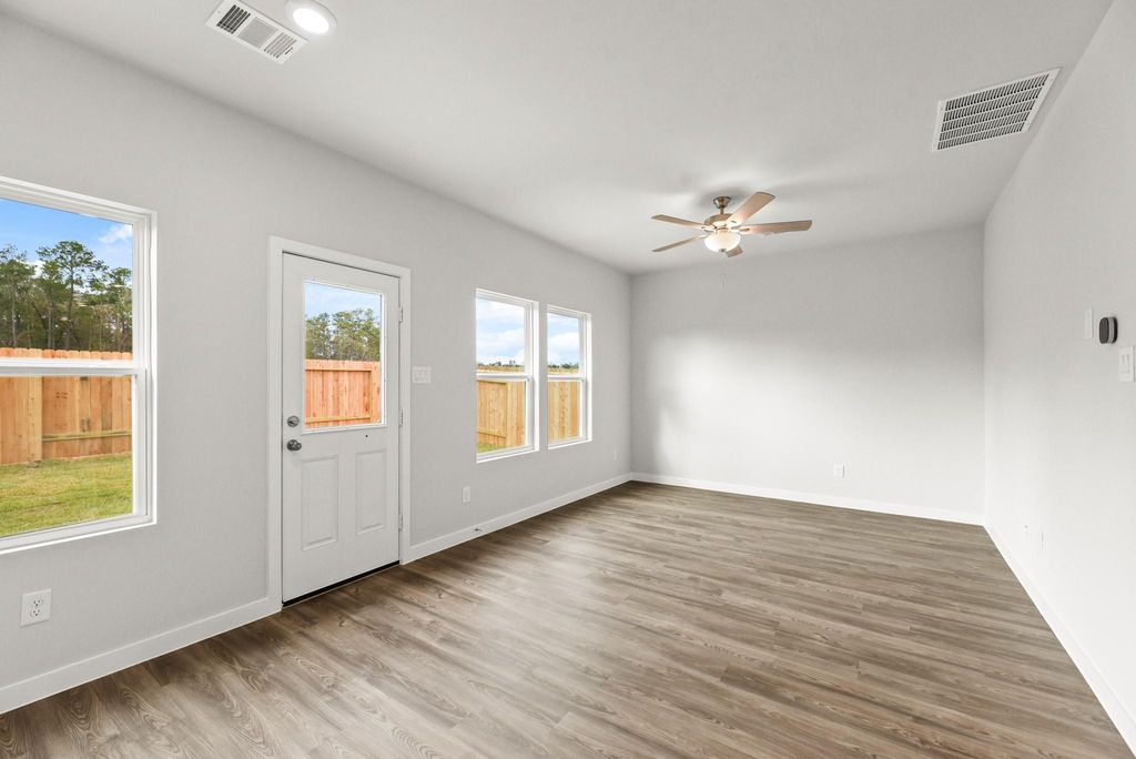 A room with a wood floor and a ceiling fan and a window.