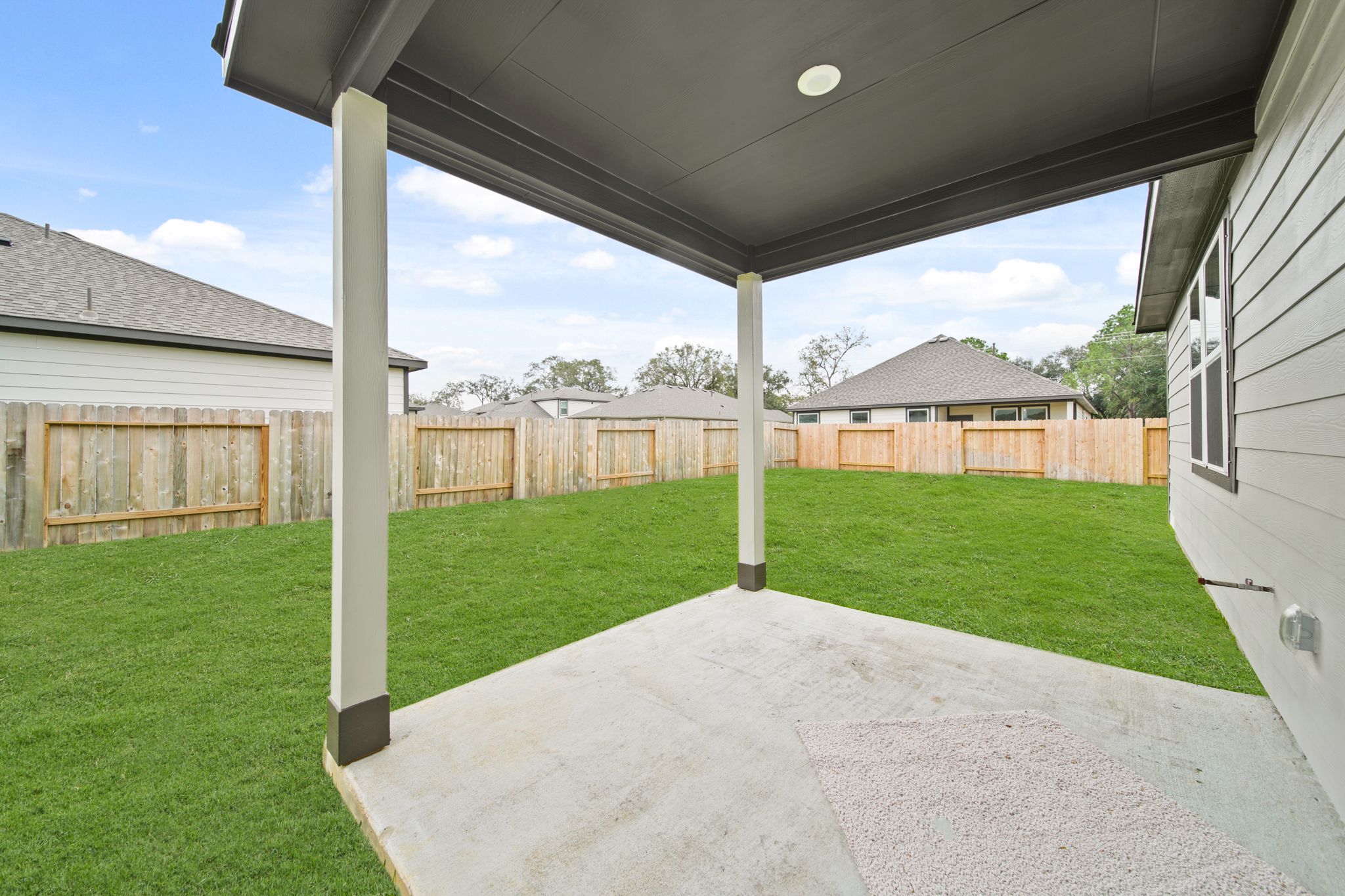 A backyard with a fence and a covered area.