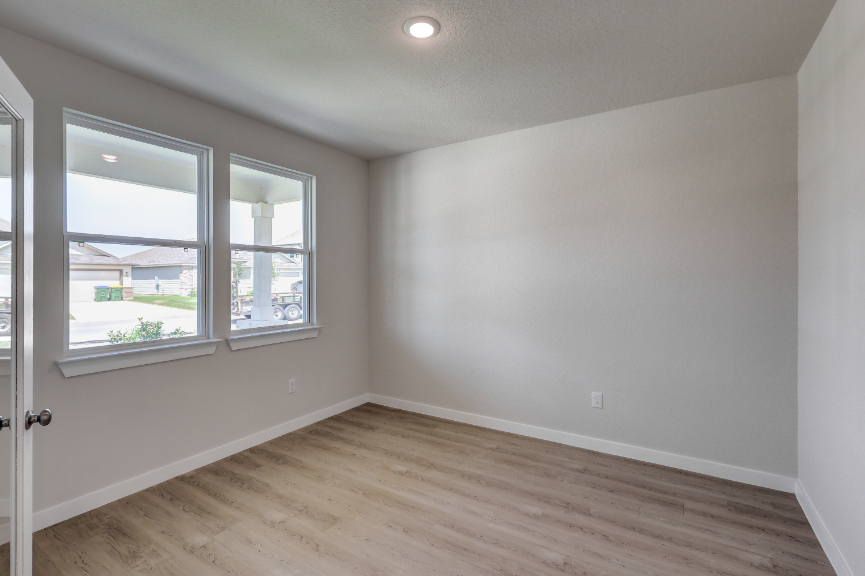 A room with a wood floor and a window with a view of the water.