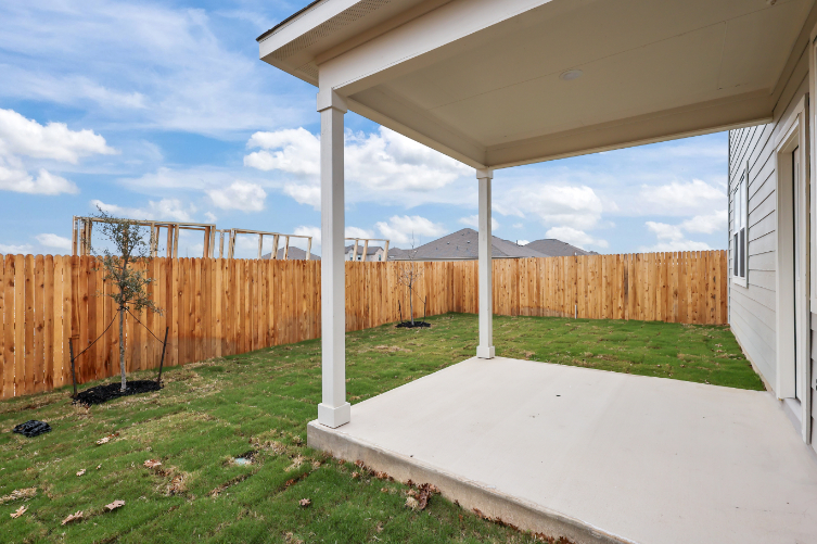A backyard with a fence and a covered patio.